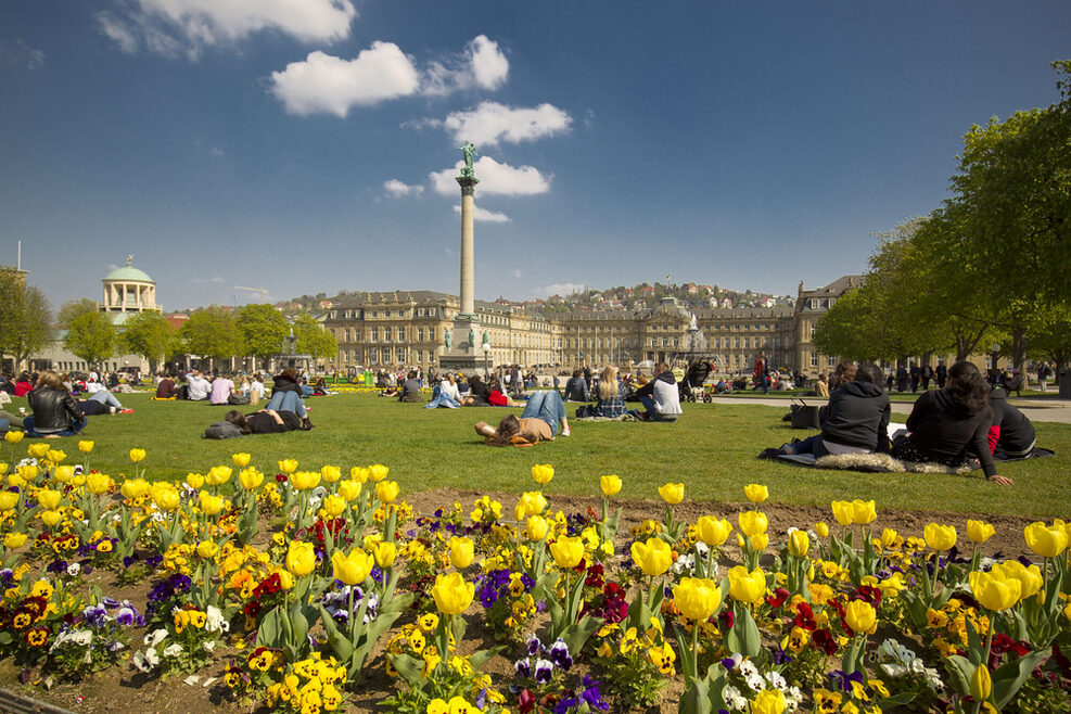 Menschen sitzen bei gutem Frühlingswetter auf dem Stuttgarter Schlossplatz