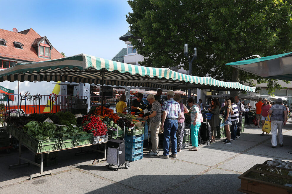 Obst- und Gemüsestände des Wochenmarkts in Weilimdorf, mit Kunden, die einkaufen.