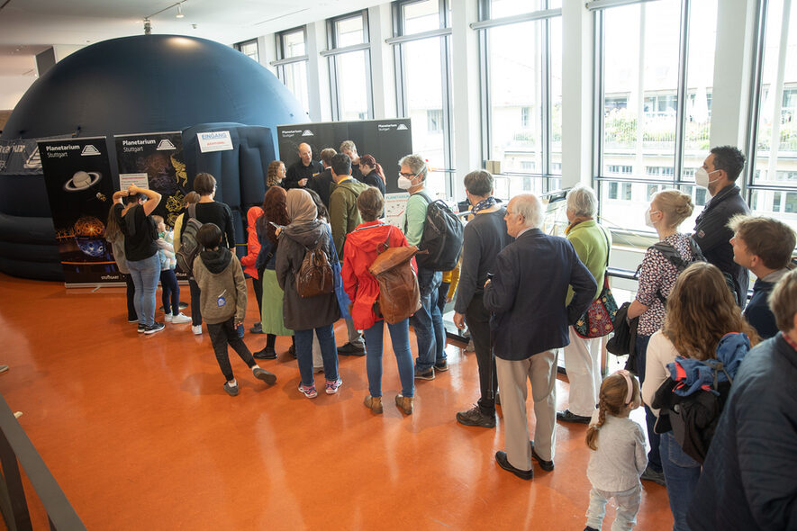 Vor einer aufblasbaren kleinen Kuppel des Planetariums stehen viele Besucher an.