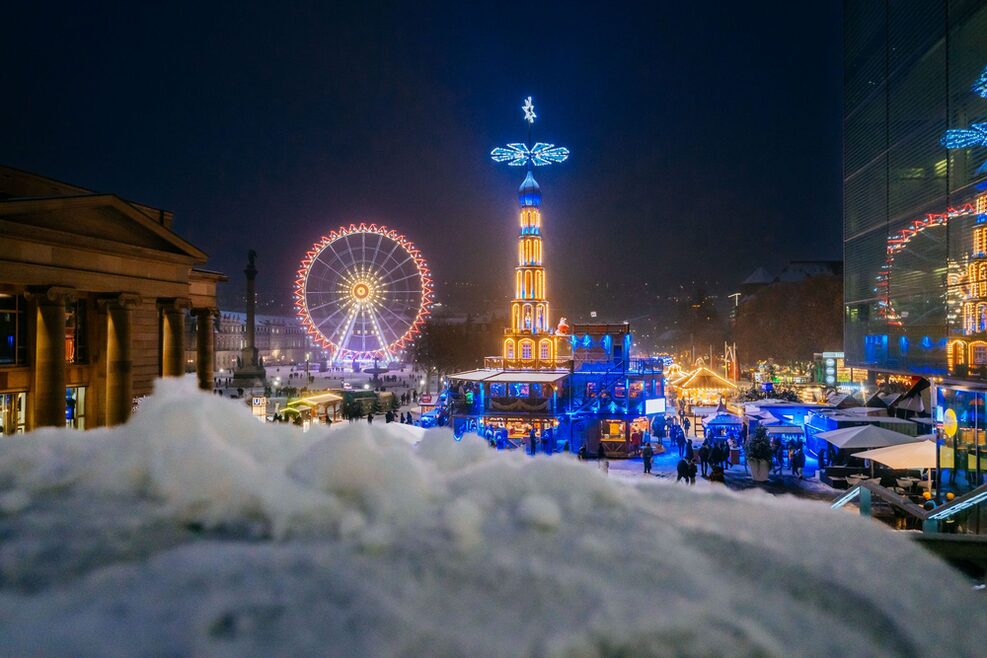 Night view of the Schlossplatz in Stuttgart with illuminated pyramid and Ferris wheel.