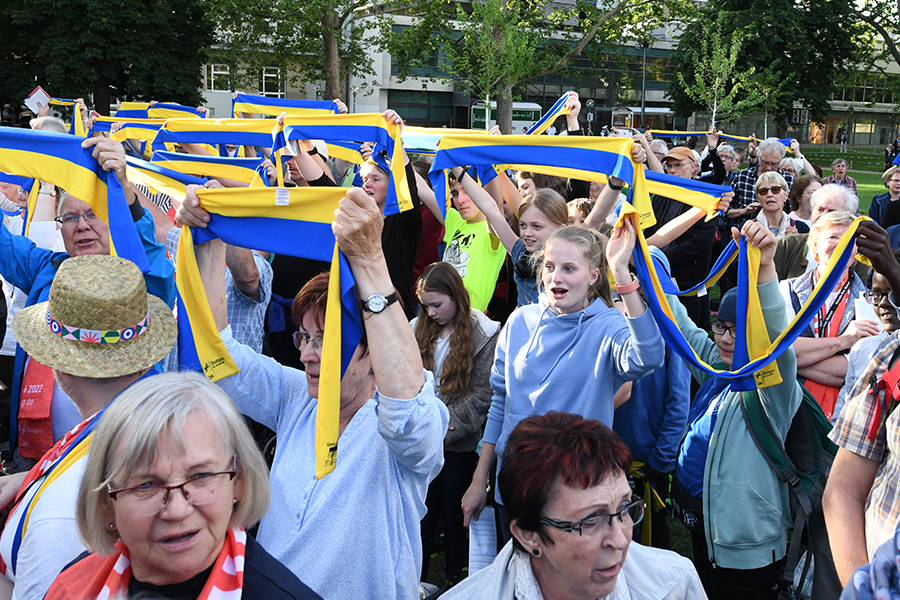 Menschen halten blau-gelbe Schals in die Luft