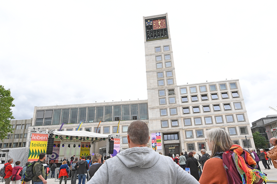 Menschen stehen vor einer Bühne, im Hintergrund das Stuttgarter Rathaus.