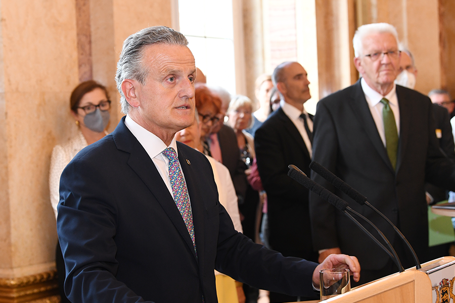 Oberbürgermeister Frank Nopper an einem Rednerpult. Im Hintergrund steht Ministerpräsident Winfried Kretschmann.