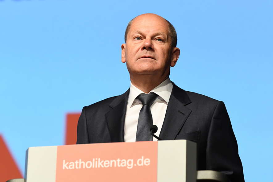 Bundeskanzler Olaf Scholz steht hinter einem Rednerpult, auf dem Pult steht: Katholikentag.de