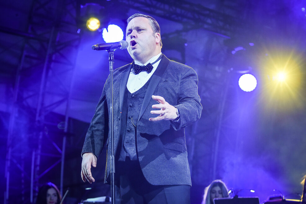 Paul Potts singend hinter einem Mikrofon.