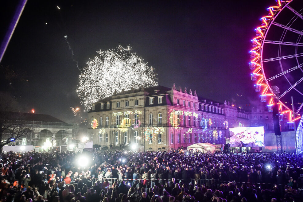 Menschenmenge vor dem illuminierten Neuen Schloss.