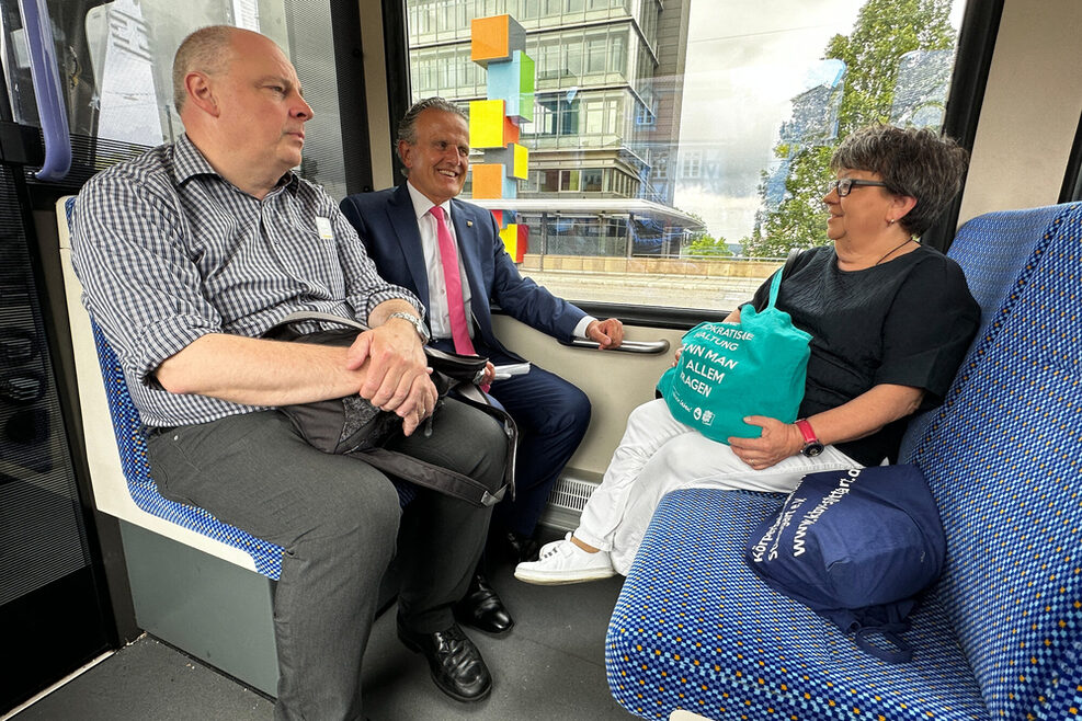 Zwei Männer und eine Frau sitzen in der Stadtbahn.