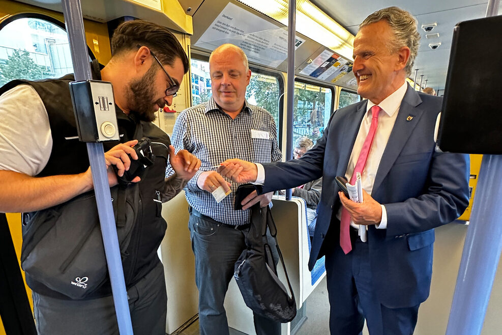 Ein Kontrolleur überprüft den Fahrschein zweier Männer in einer Stadtbahn.