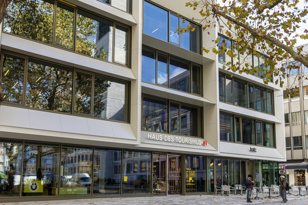 Moderne Außenfassade des Haus des Tourismus am Marktplatz in Stuttgart. In der großen Fensterfront spiegelt sich der Marktplatz mit dem Rathausturm wieder.
