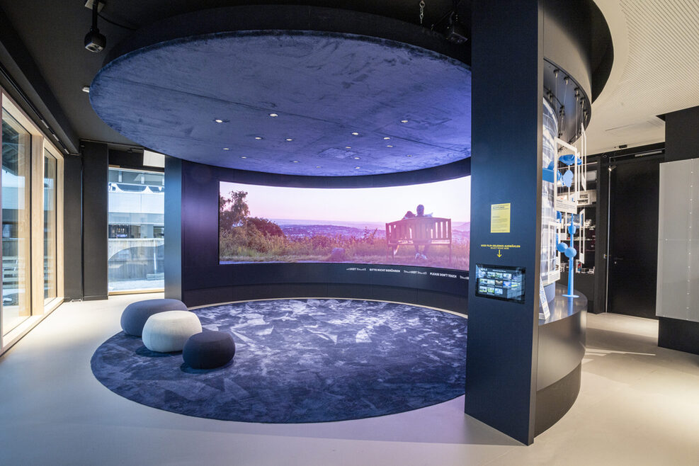 180-Grad‐LED‐Wand in der Tourist‐Information i‐Punkt im Haus des Tourismus mit drei Sitzhöckern. Auf der Leinwand läuft ein Video zur Tourismus-Region Baden-Württemberg.