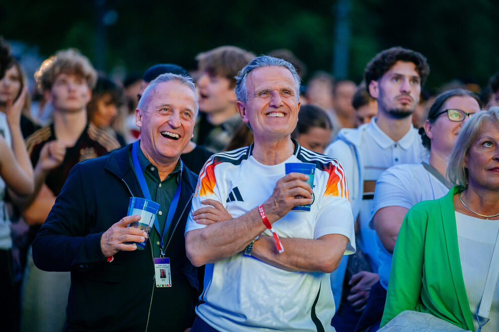Zwei Männer stehen freudestrahlend zwischen den deutschen Fans.