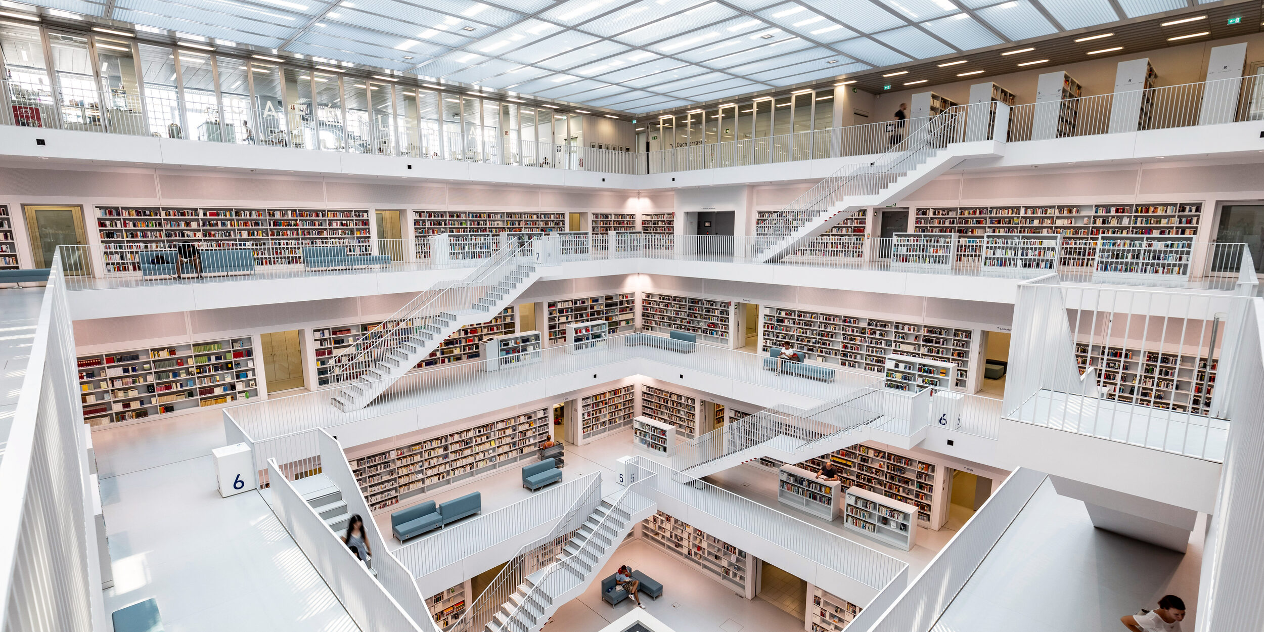 Der Innenraum der Stadtbibliothek hat eine Galerie über mehrere Ebenen mit Freitreppen. Alles ist in Weiß. Nur die Buchrücken setzen Farbakzente.