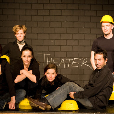 fünf Frauen und zwei Männer in schwarzen Hemden ahben gelbe Bauhelme dabei und schauen in die Kamera