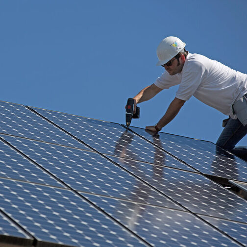 Ein Mann befestigt Solarpanelen auf einem Dach.
