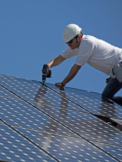 Ein Mann befestigt Solarpanelen auf einem Dach.