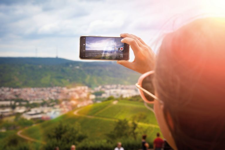 Eine Frau macht ein Foto mit ihrem Handy von den Weinbergen.