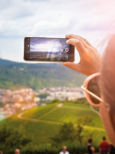 Eine Frau macht ein Foto mit ihrem Handy von den Weinbergen.
