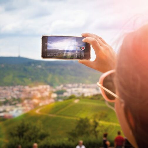 Eine Frau macht ein Foto mit ihrem Handy von den Weinbergen.