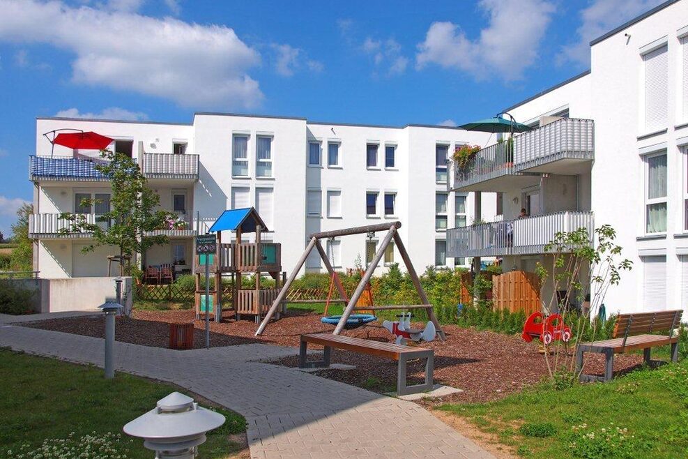Flachdach-Neubauten mit Kinderspielplatz.