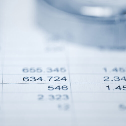 Lupe auf Papier mit Tabellen und Zahlen