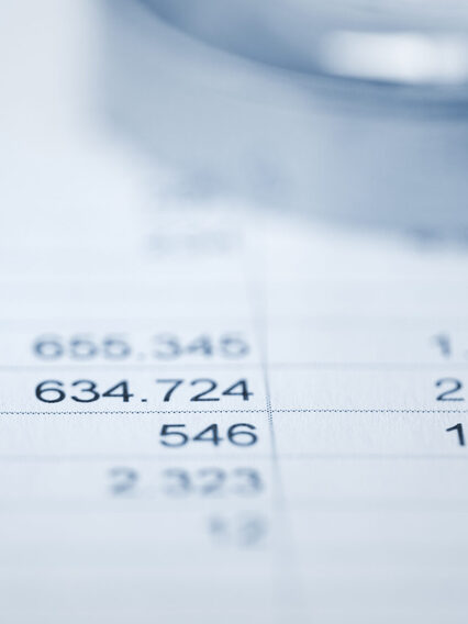 Lupe auf Papier mit Tabellen und Zahlen