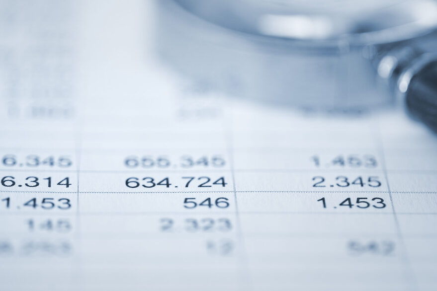 Lupe auf Papier mit Tabellen und Zahlen