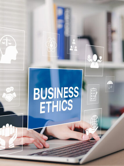Geschäftsmann nutzt Laptop mit transparenten Symbolen, die für unternehmerische Verantwortung, Ethik, Integrität, Grundwerte stehen.