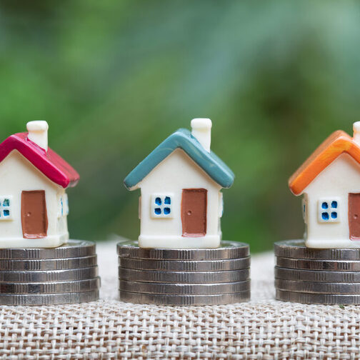 Miniature houses between piles of coins