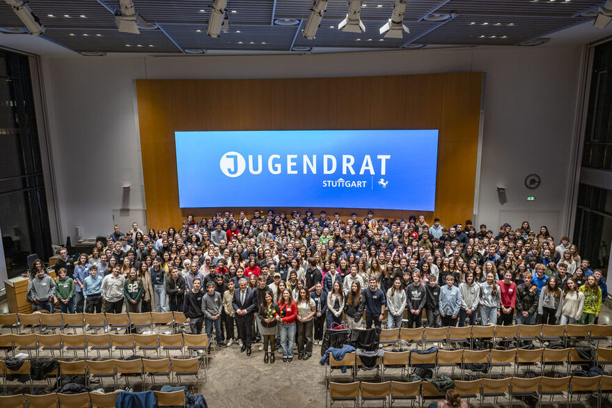Die ausgeschiedenen und neu gewählten Jugendrätinnen und Jugendräte machen ein gemeinsames Bild mit dem Oberbürgermeister. Sie stehen alle vor dem Jugendratslogo.