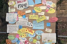 Pinwand hängt an einem Zaun mit vielen verschiedenen Zetteln mit Ideen.