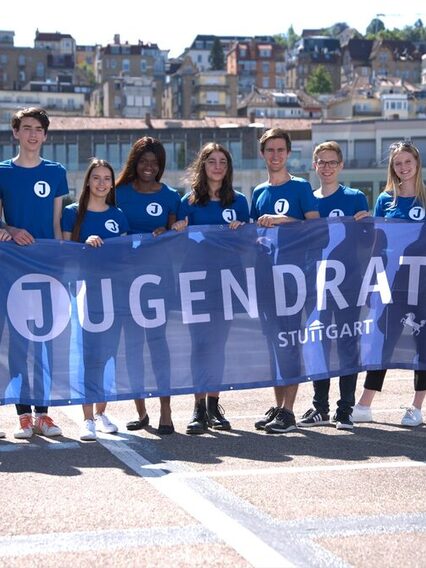 Gruppenfoto Jugendrat Stuttgart: Mitglieder stehen nebeneinander und halte ein Banner mit der Aufschrift "Jugendrat"