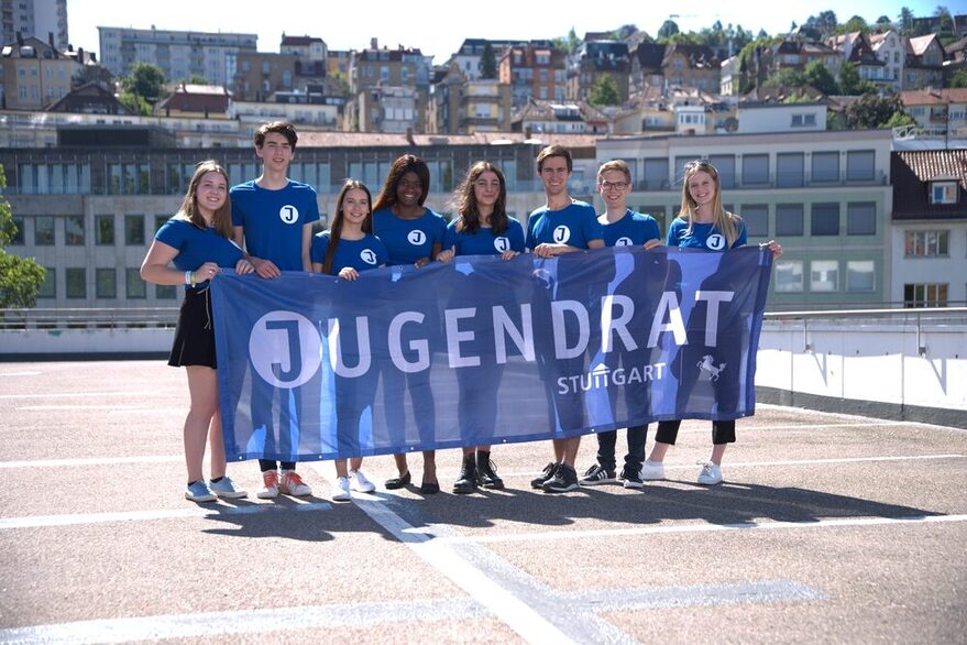 Gruppenfoto Jugendrat Stuttgart: Mitglieder stehen nebeneinander und halte ein Banner mit der Aufschrift "Jugendrat"