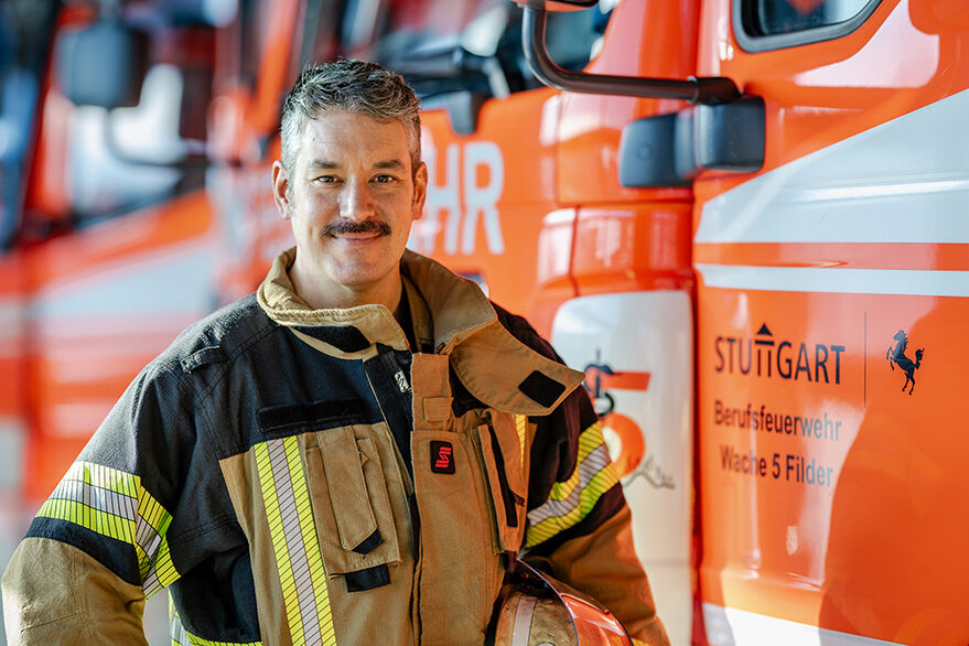Ein Feuerwehrmann steht vor einen Feuerwehrauto.