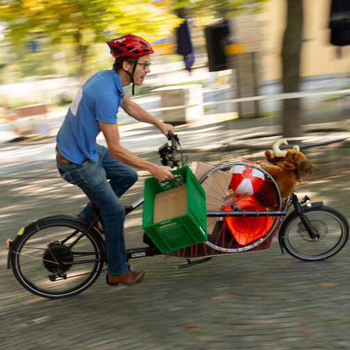 Ein Mann fährt mit einem beladenen Lastenrad über einen Platz.