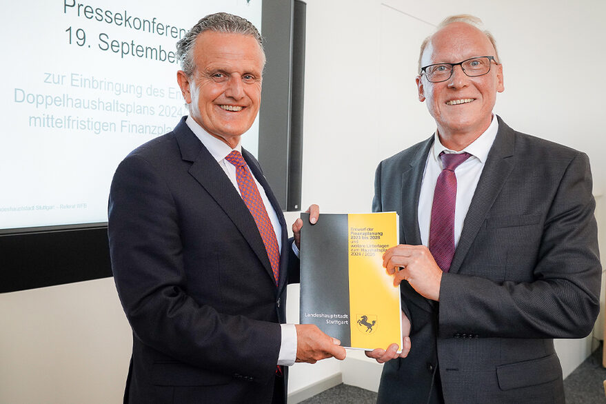 OB Frank Nopper und BM Thomas Fuhrmann halten lächelnd den Entwurf zum Doppelhaushalt 2024/2025 in Händen.