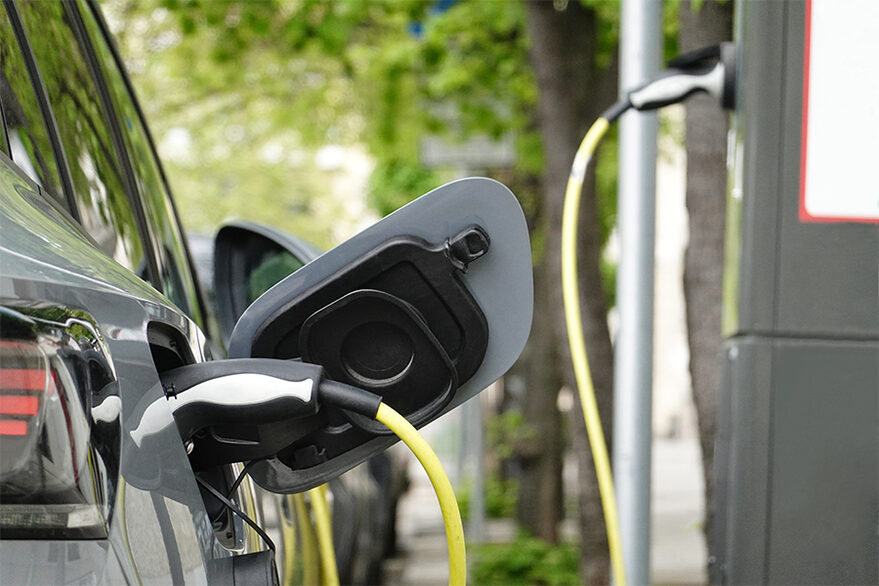 Das Foto zeigt die Rückseite eines Elektroautos beim Ladevorgang an einer Ladesäule.