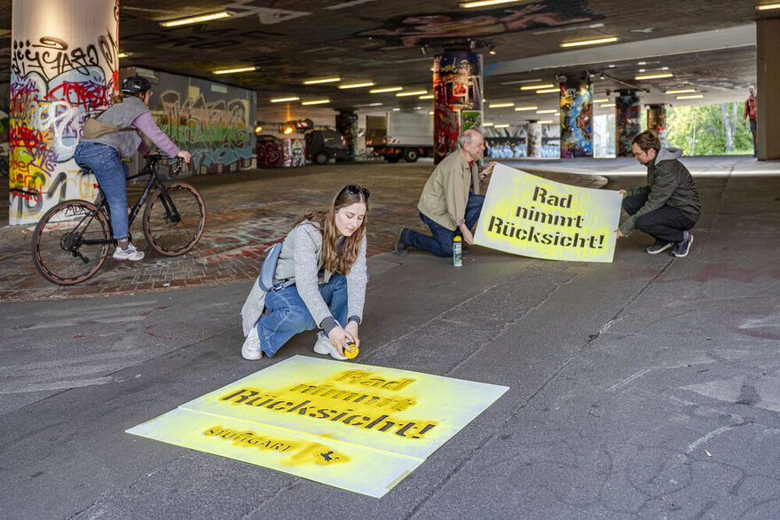 Der Spruch "Rad nimmt Rücksicht!" mit gelber Farbe auf Asphalt gesprayt.
