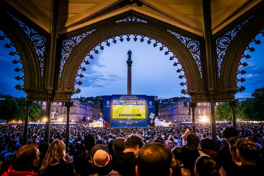 Eine Menschenmenge auf dem Schlossplatz schaut auf eine große Leinwand, auf der ein Fußballspiel übertragen wird.