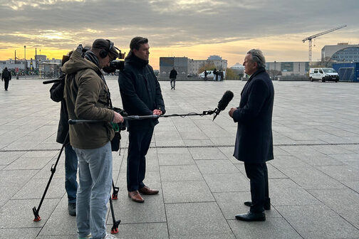 Mayor Frank Nopper gives a television interview, with the Federal Chancellery in the background.