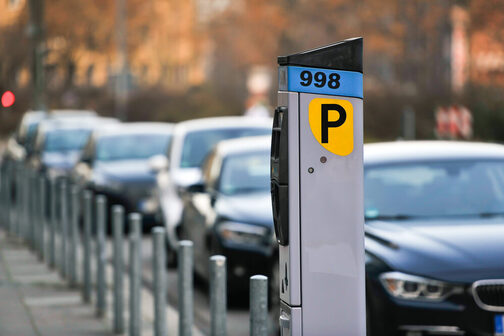 Автомат по продаже парковочных билетов на тротуаре в центре Штутгарта. Автомобили припаркованы у края.