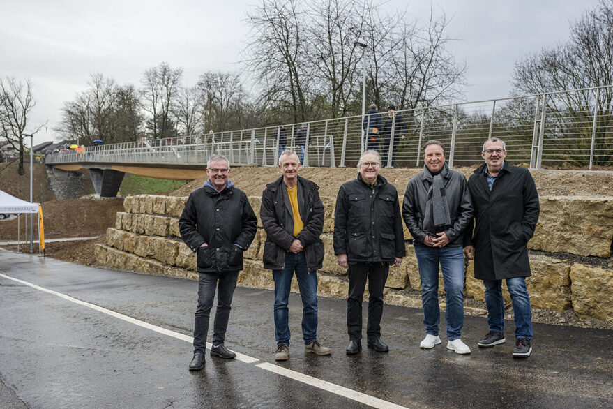Eröffnung des Stegs über den Seeblickweg: (v.l.) Andreas Hofer (Intendant der IBA’27), Ralf Bohlmann (Bezirksvorsteher von Mühlhausen), Jürgen Mutz (Leiter des Städtischen Tiefbauamtes) und Peter Pätzold (Bürgermeister für Städtebau, Wohnen und Umwelt) schreiten über den neuen Steg.