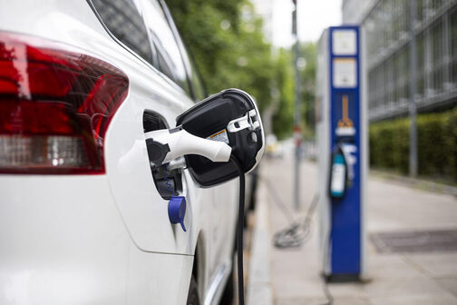 Auto steht vor einer E-Ladesäule und wird aufgeladen.