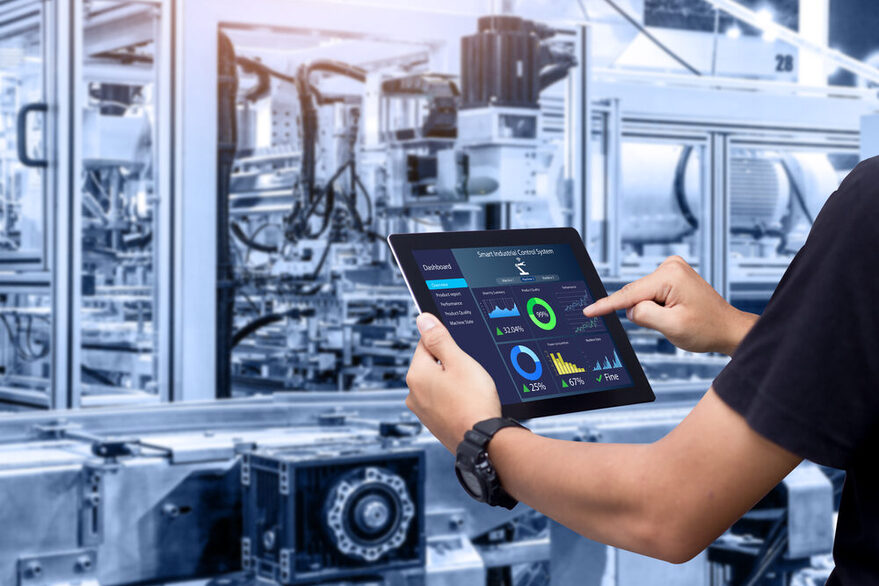 Eine Person bedient auf einem Tablet ein industriellen Roboter.