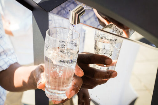 The picture shows a male hand drawing fresh water from a drinking fountain.