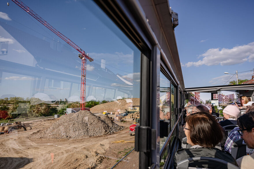 Die mitfahrenden Gäste betrachten aus dem Busfenster eine Baustelle.