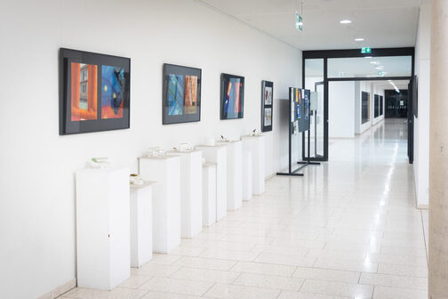 A bright, white hallway. Pictures hang on the walls.