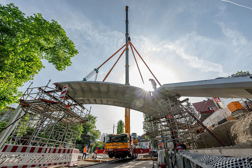 Das Foto zeigt die Montage des ersten Brückenelements am Neubau des Geh- und Radwegstegs über die Kaltentaler Abfahrt.