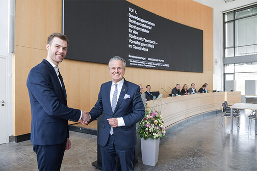 The photo shows the new district leader of Feuerbach, Nick Gumenick, and Lord Mayor Dr. Frank Nopper being congratulated on their election by the municipal council in the main meeting room.