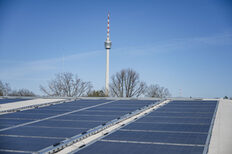 Ein Dach mit einer Photovoltaikanlage. Im Hintergrund der Stuttgarter Fernsehturm.
