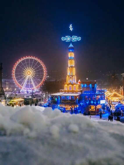 Night view of the Schlossplatz in Stuttgart with illuminated pyramid and Ferris wheel.